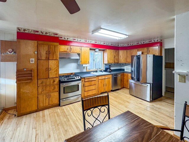 kitchen featuring ceiling fan, sink, stainless steel appliances, and light wood-type flooring