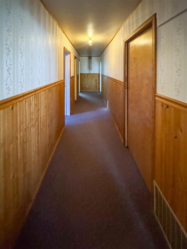 hallway with carpet and wood walls