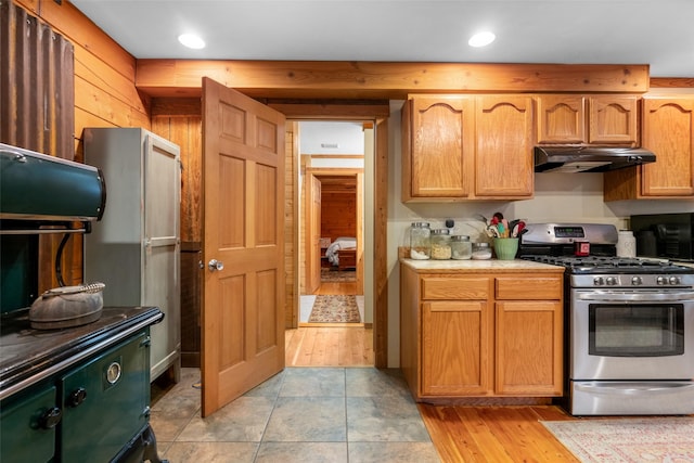 kitchen featuring stainless steel gas range and wood walls