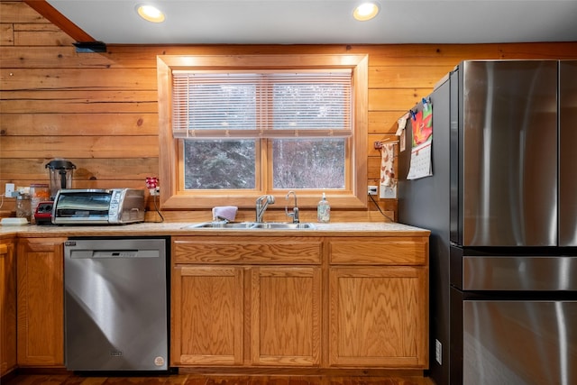 kitchen featuring sink, wooden walls, and appliances with stainless steel finishes