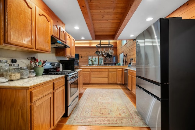 kitchen with beamed ceiling, appliances with stainless steel finishes, light hardwood / wood-style floors, and kitchen peninsula