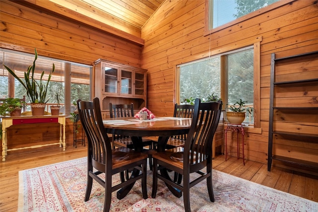 dining area featuring wooden ceiling, wooden walls, high vaulted ceiling, and light wood-type flooring