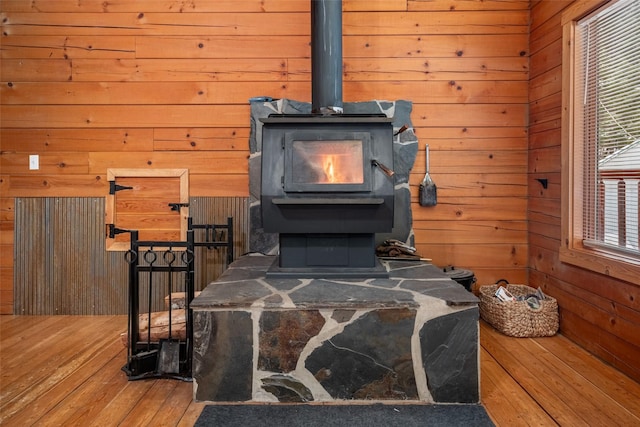 room details featuring hardwood / wood-style floors, a wood stove, and wood walls