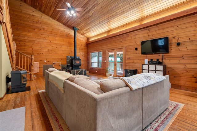 living room with vaulted ceiling, a wood stove, and light hardwood / wood-style flooring