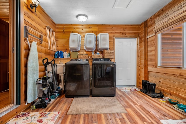 laundry area featuring hardwood / wood-style flooring, washer and clothes dryer, and wood walls