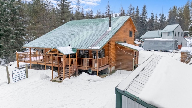 snow covered back of property with a porch