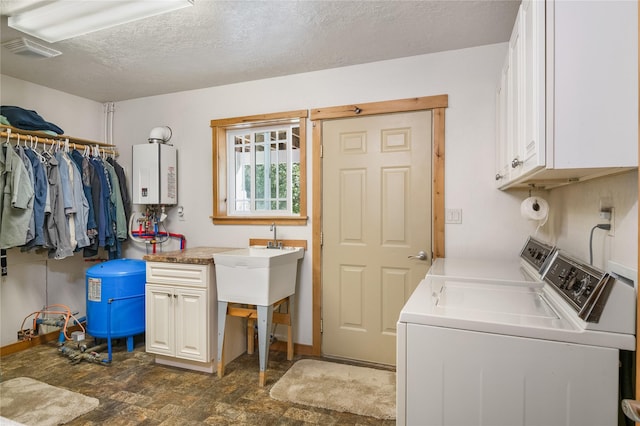 clothes washing area with washer and dryer, cabinets, a textured ceiling, and water heater