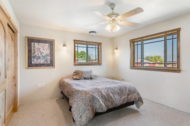 bedroom with ceiling fan, a closet, and light colored carpet