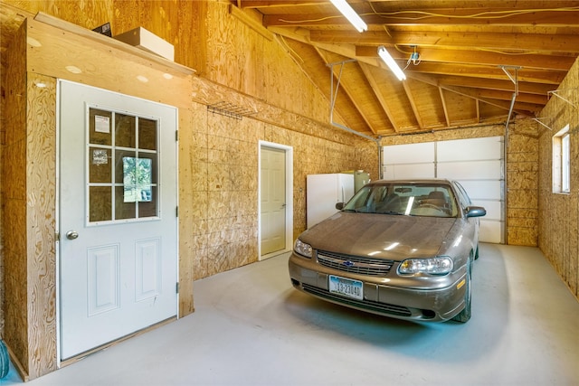 garage featuring wood walls and white fridge