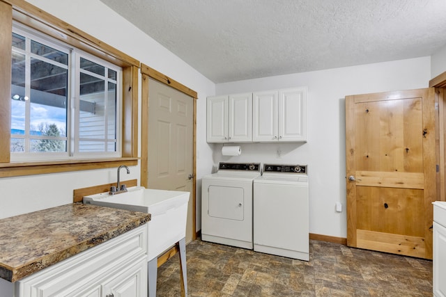 358 Hamilton Heights Rd, Corvallis, MT 59828 - laundry area featuring stone finish floor, a textured ceiling, cabinet space, baseboards, and washer and clothes dryer