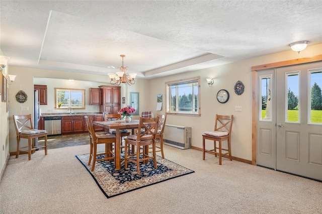 carpeted dining room with a notable chandelier, a raised ceiling, sink, and a wealth of natural light