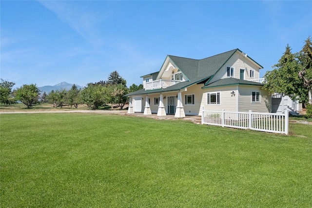 view of front of house featuring a mountain view, a balcony, and a front lawn