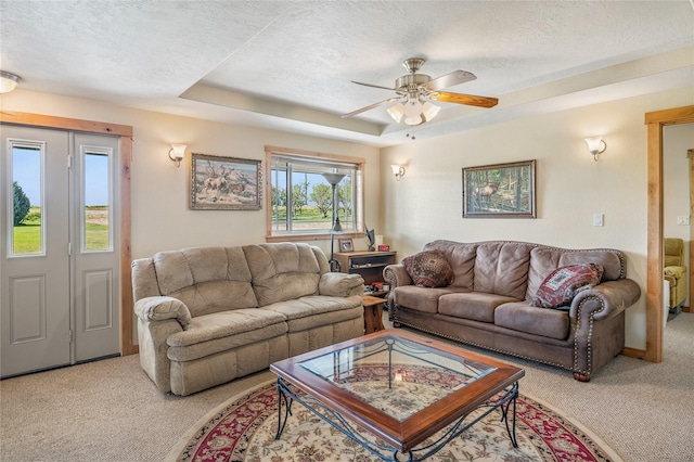 carpeted living room featuring ceiling fan, a textured ceiling, and a tray ceiling