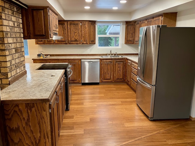 kitchen featuring light stone countertops, light wood-type flooring, appliances with stainless steel finishes, and sink