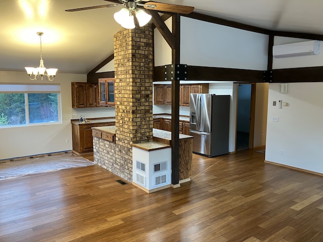 kitchen with hardwood / wood-style flooring, stainless steel fridge, a wall unit AC, lofted ceiling, and hanging light fixtures