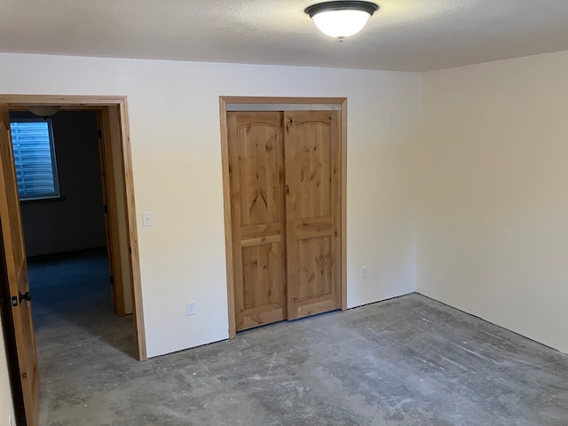 unfurnished bedroom with a textured ceiling, a closet, and concrete flooring