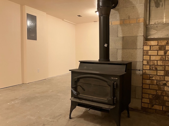 room details featuring concrete floors, a wood stove, and electric panel