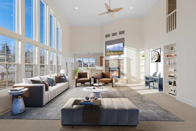 living room with carpet flooring, a towering ceiling, a stone fireplace, and built in features