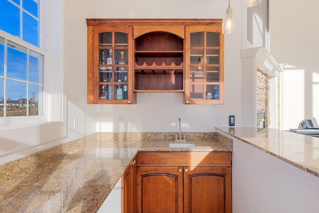 kitchen featuring sink, light stone countertops, and hanging light fixtures