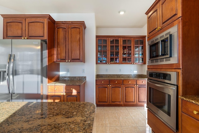 kitchen with dark stone counters, light tile patterned flooring, and stainless steel appliances