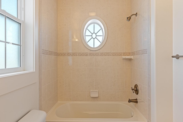 bathroom with a healthy amount of sunlight, tiled shower / bath combo, and toilet