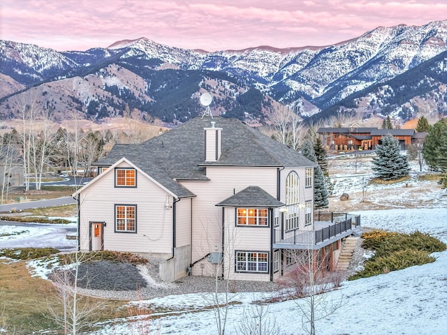 snow covered back of property with a mountain view and a balcony