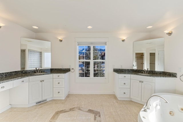 bathroom featuring tile patterned flooring, vanity, a bathtub, and vaulted ceiling