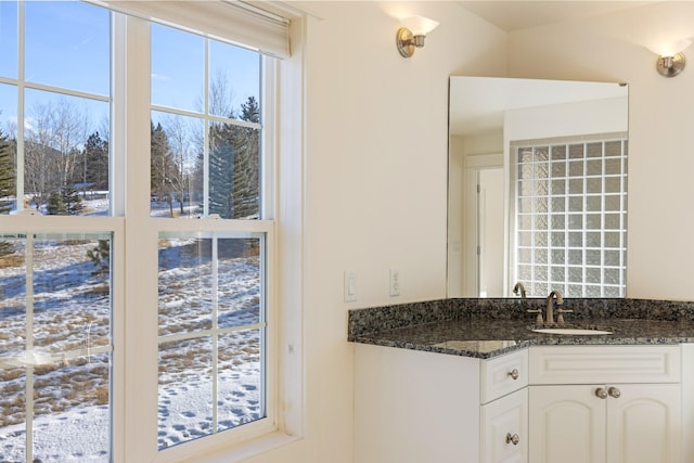 kitchen featuring dark stone countertops, sink, and white cabinets