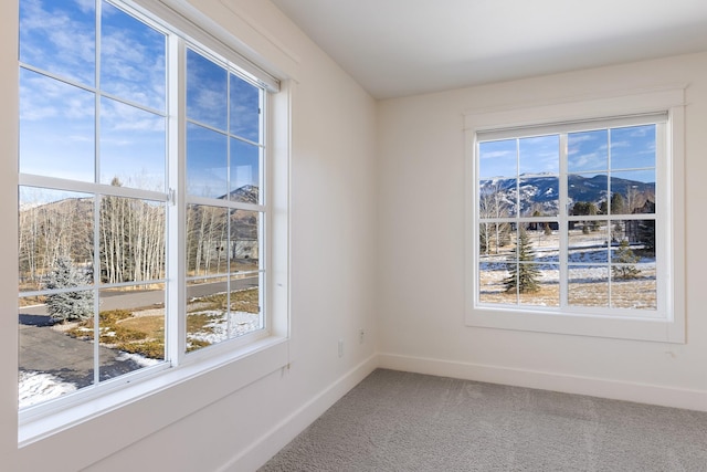 empty room with a mountain view, carpet floors, and plenty of natural light