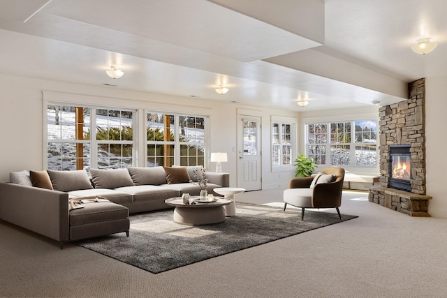 carpeted living room featuring a stone fireplace