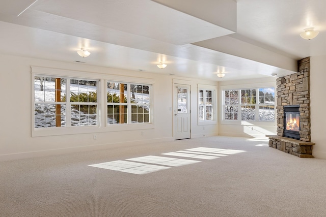 unfurnished living room featuring light colored carpet and a stone fireplace