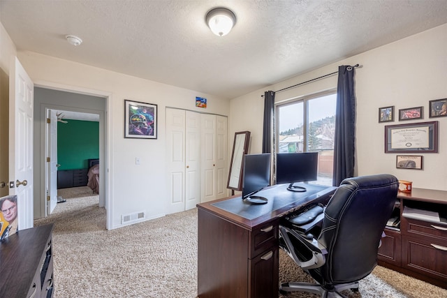 carpeted office featuring a textured ceiling