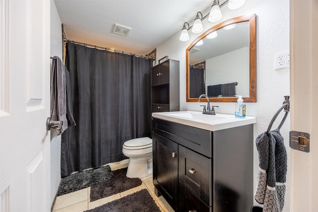 bathroom with tile patterned floors, vanity, a textured ceiling, and toilet