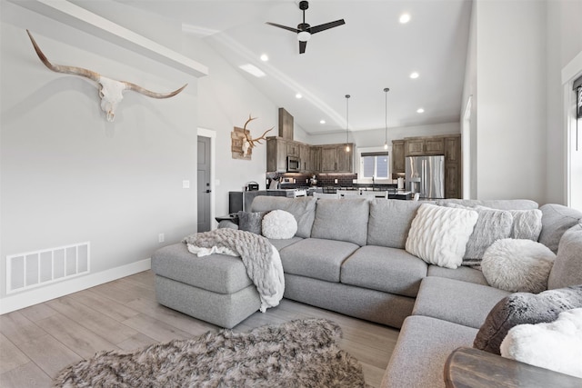 living room featuring high vaulted ceiling, light hardwood / wood-style floors, and ceiling fan