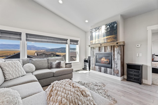 living room with lofted ceiling, a mountain view, and light wood-type flooring