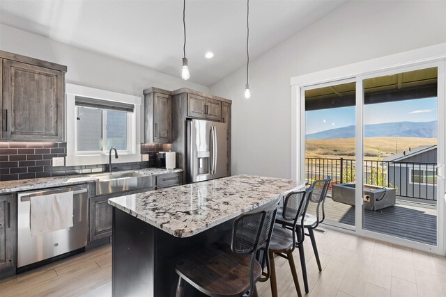 kitchen with dark brown cabinets, appliances with stainless steel finishes, a mountain view, and a kitchen island