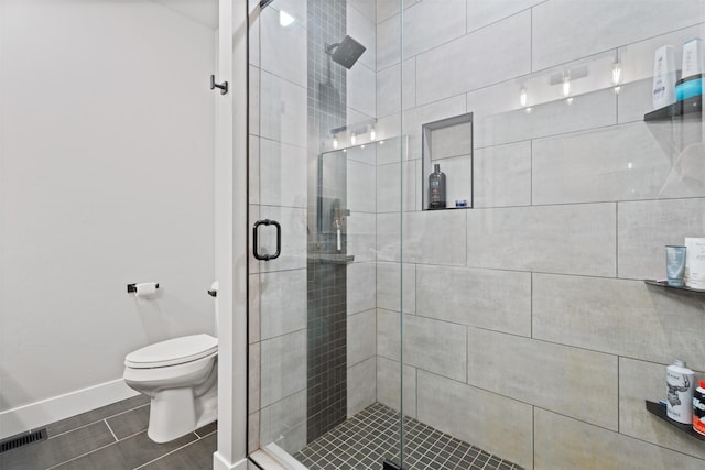 bathroom featuring toilet and a shower with door