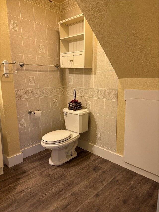 bathroom with hardwood / wood-style flooring, toilet, lofted ceiling, and tile walls