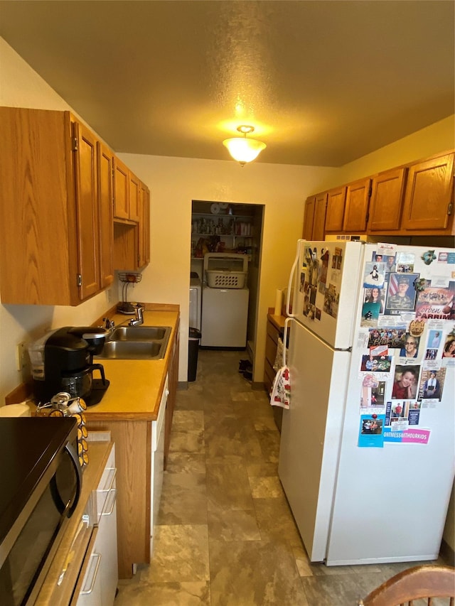 kitchen with white fridge, independent washer and dryer, and sink