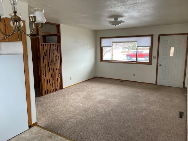 foyer featuring a chandelier, light colored carpet, and a textured ceiling