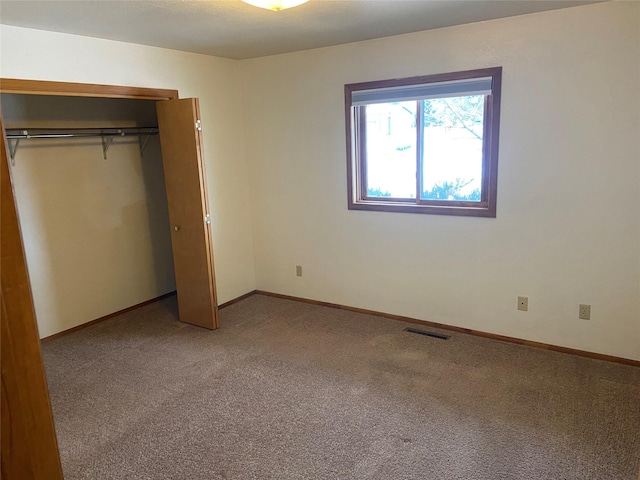 unfurnished bedroom with a closet and light colored carpet