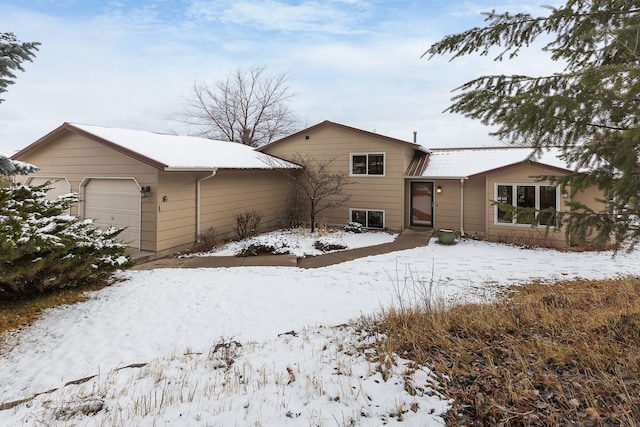 snow covered back of property with a garage