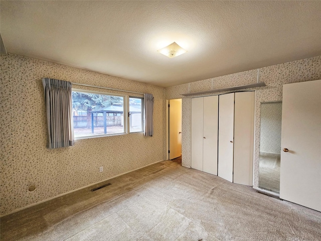 unfurnished bedroom featuring a textured ceiling and light carpet