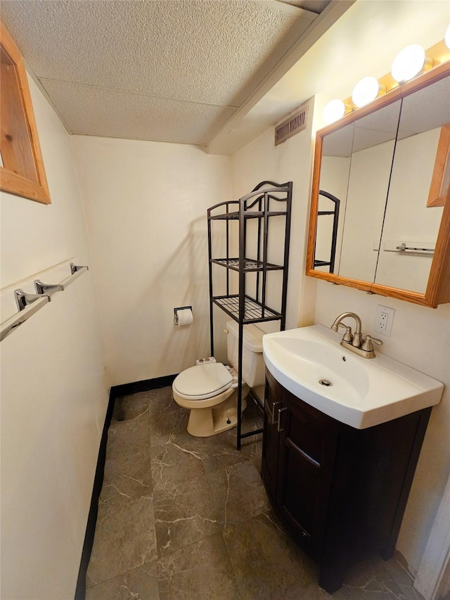 bathroom with vanity, toilet, and a textured ceiling