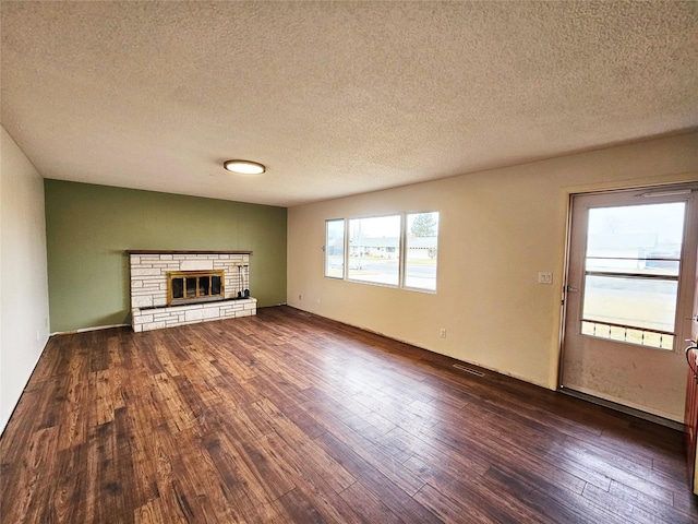 unfurnished living room with a textured ceiling, dark hardwood / wood-style flooring, and a fireplace