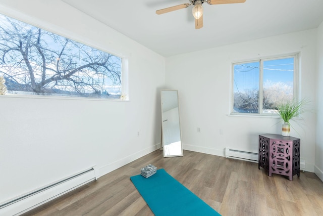 workout area featuring hardwood / wood-style flooring, ceiling fan, and a baseboard heating unit