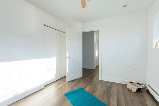 bedroom featuring hardwood / wood-style flooring, ceiling fan, a closet, and a baseboard heating unit