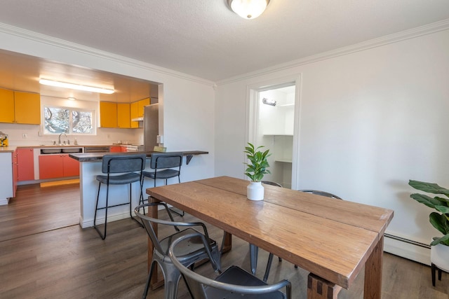 dining room featuring sink, crown molding, baseboard heating, and dark wood-type flooring