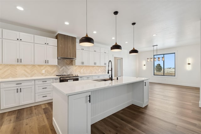 kitchen with a center island with sink, a sink, white cabinetry, and stainless steel electric stove