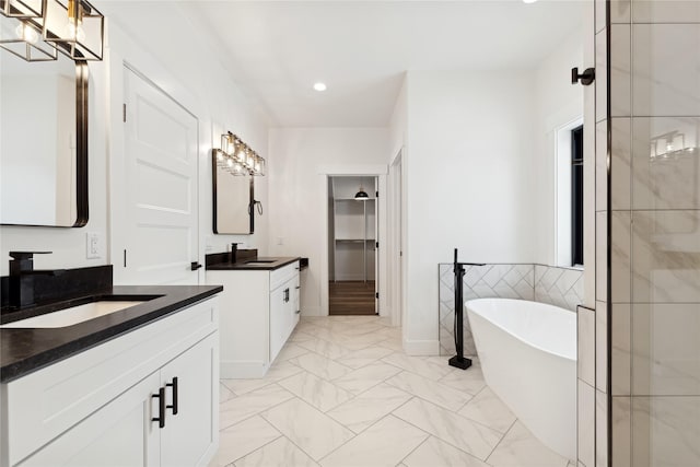 full bath with marble finish floor, two vanities, a sink, and a freestanding bath